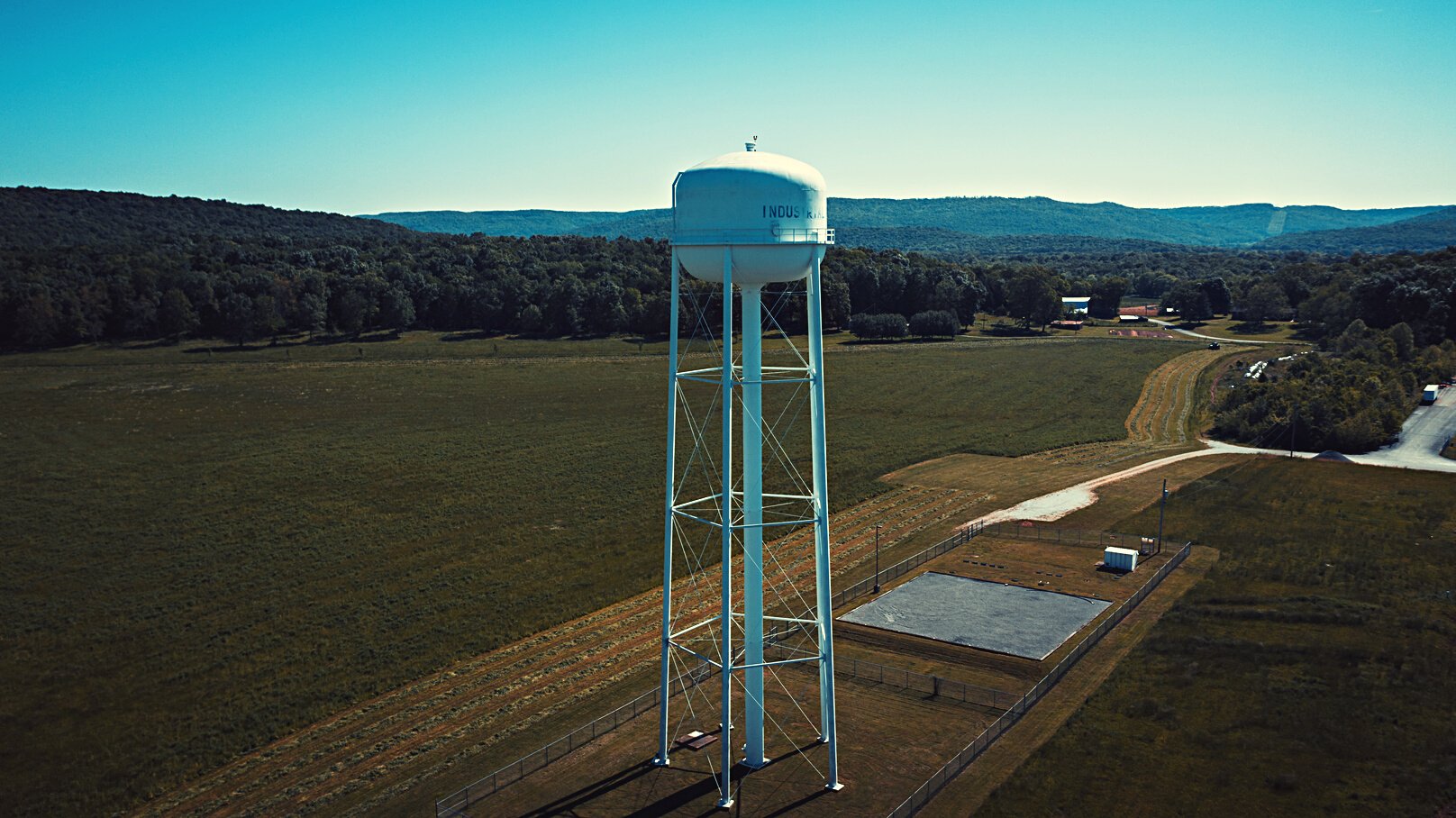 Elevated water tank on green lawn in industrial park